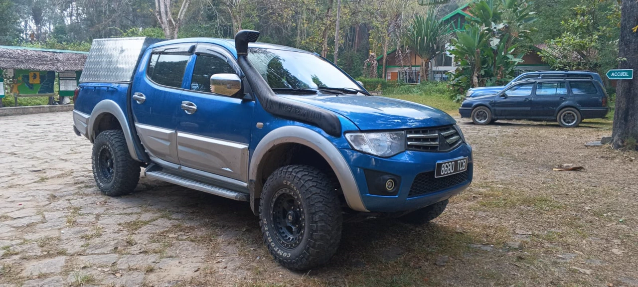 Mitsubishi L200 pickup driving on a red clay track in Madagascar